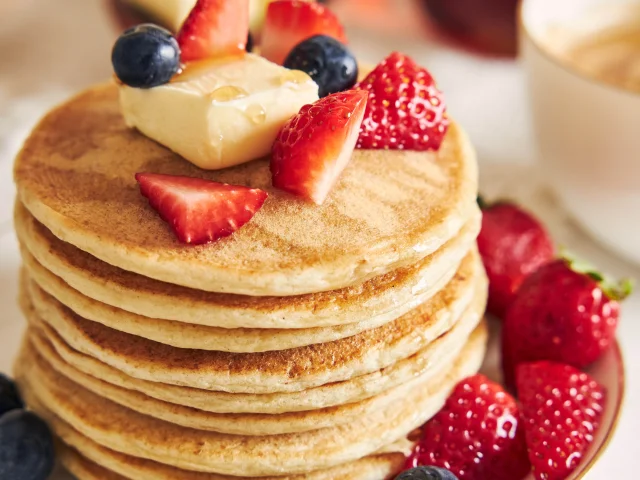 A vertical shot of vegan tofu pancakes with fruits on a white plate